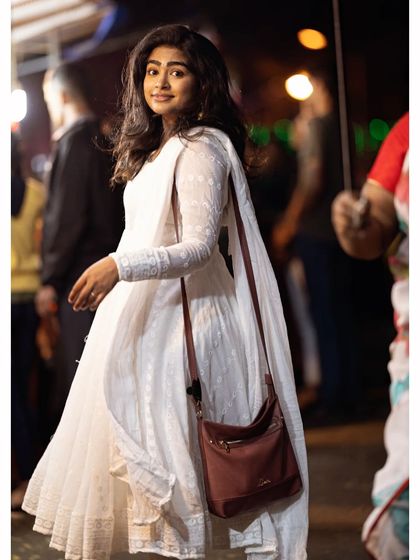 A full view of a simple and elegant look for an evening out. The white Anarkali is paired with minimal makeup, focusing on clean skin and a happy glow.