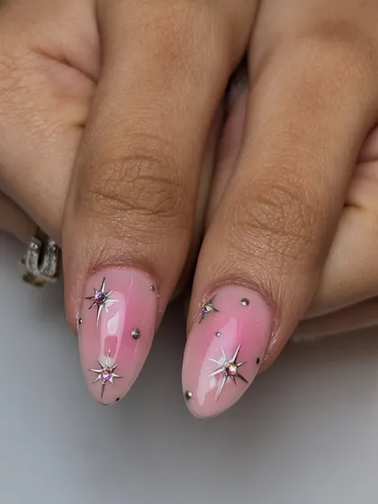 A celestial design featuring a soft pink ombré base with chrome starbursts and sparkling gems. This look combines airbrushing, chrome, and 3D embellishments.