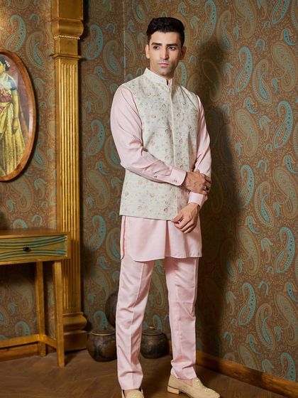 A light pink kurta paired with a taupe-colored bundi featuring fine floral embroidery. This is a charming and elegant choice for a day event or a destination wedding.