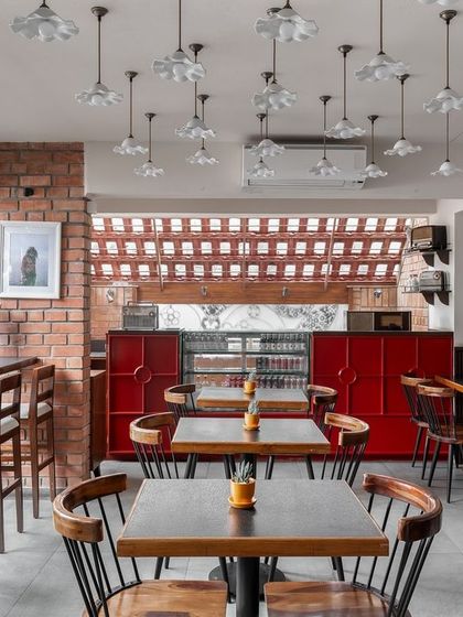 The interior of Klaa Kitchen, where we used a mix of exposed brick, a bright red counter, and art deco-inspired pendant lights. The design is an ode to Goa with Portuguese references and a warm, inviting ambiance.