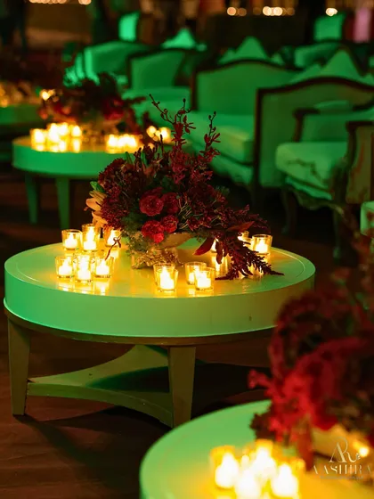 The green lighting adds a unique mood to this lounge area, where the tables are adorned with red floral centerpieces and glowing candles.