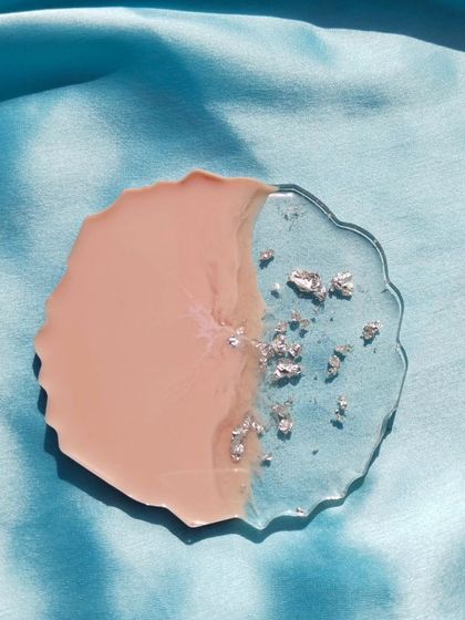 This single geode coaster showcases a simple yet elegant design, pairing a soft pink hue with a clear section filled with shimmering silver flakes.