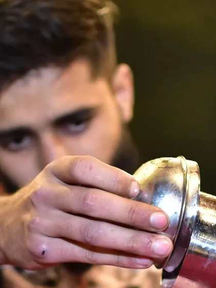 A close-up shot of a mixologist pouring from a shaker. This highlights the intense focus and precision that goes into the craft of cocktail making.