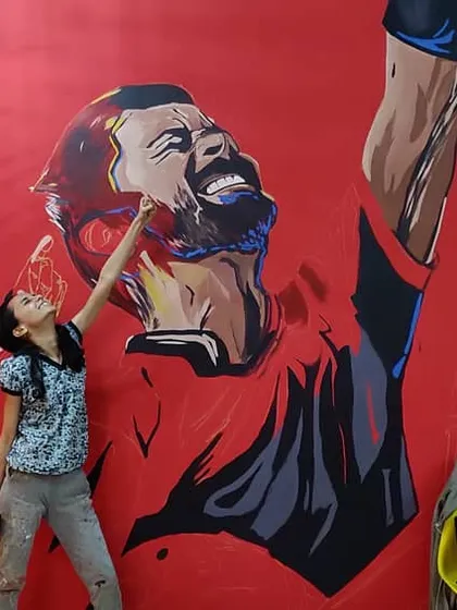 Bhavishya adding the finishing touches to Virat Kohli's face. This work in progress shot shows the scale of the RCB mural.