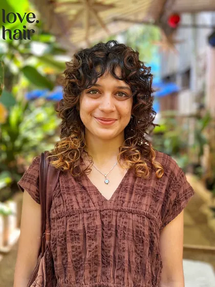 Yes, you can have bangs with curly hair. We specialize in modern, edgy styles like this curly shag with a fringe, cutting it to work with your natural texture, not against it.