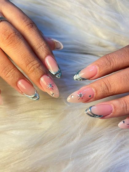 A different view of our 3D silver chrome nails, showing how the metallic elements catch the light. The combination of chrome, stars, and rhinestones on a neutral base is a modern and edgy choice.