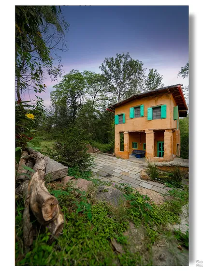 Another view of the "Tiny Norah" farm stay, capturing its quaint and rustic charm from a different angle. The image emphasizes its seclusion and connection to the surrounding natural environment.