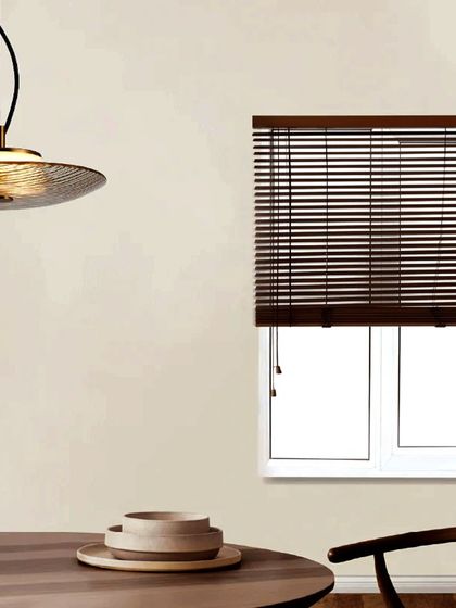 A saucer-shaped pendant with a textured glass finish provides soft, diffused light over a dining table. This minimalist design is a beautiful example of luxury hanging delicately.