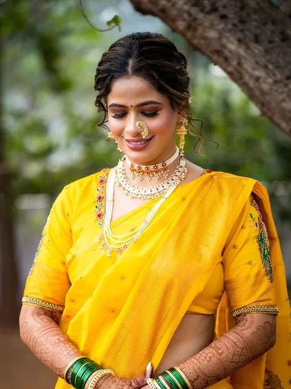 A classic pose for a Maharashtrian bride. The makeup is timeless, with warm, earthy tones that complement the yellow saree and traditional jewellery.