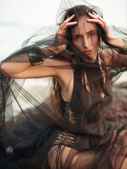 A mysterious and alluring portrait, with the model partially obscured by the sheer black fabric. This creative shot plays with texture and transparency.