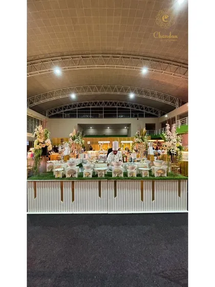A panoramic view of a beautifully decorated chaat counter at a large event, showcasing the variety of toppings and ingredients available for guests to customize their snacks.