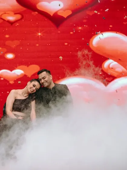 A dreamy Sangeet performance, with the couple enveloped in stage smoke against a backdrop of hearts. This captures the glamour and romance of your evening celebrations.