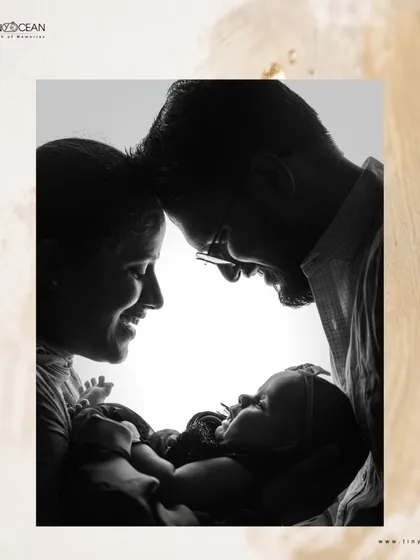 This is the art of connection. A beautiful black and white silhouette captures the pure love between new parents as they gaze down at their baby, their faces forming a circle of love around their new world.