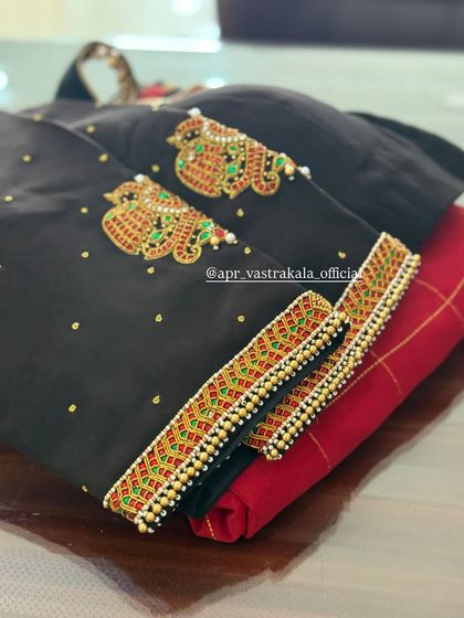 The sleeves of this black blouse feature kalash motifs created with red and green temple-style embroidery.