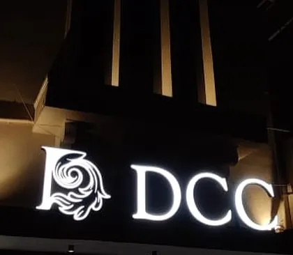 The illuminated 'DCC' logo for Dreamz City Chambers at night. This final detail is the culmination of a long process, from navigating a difficult site to adding the finishing touches that define the building's identity.