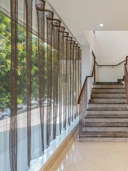 An undulating mesh curtain was introduced along the glass facade of the Nalli store. This element controls the intense glare of the Chennai sun while adding a layer of translucency and texture to both the interior and exterior.