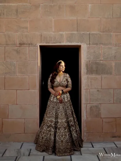 A beautiful bridal portrait taken against a historic stone wall. The bride's regal pose and the warm, natural light create an image of timeless elegance.