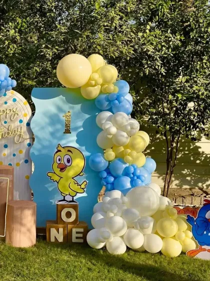 This view highlights the layered backdrops and the full balloon garland of our duckling-themed first birthday party.