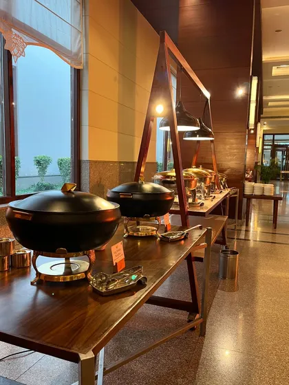 A different style of buffet setup, with black and gold serving dishes on a rustic wooden and metal frame.