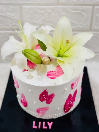 A simple and stunning cake named "Lily," adorned with fresh white lilies and abstract pink brushstrokes for an artistic touch.