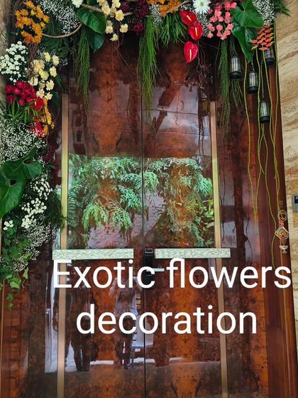 A rustic and colorful door frame decoration. This design combines bright flowers with hanging greenery and small lanterns for a unique and eclectic look.