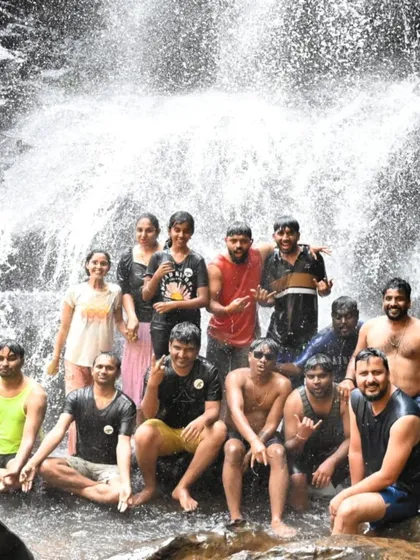 A group of friends soaked and happy after a dip in a waterfall.