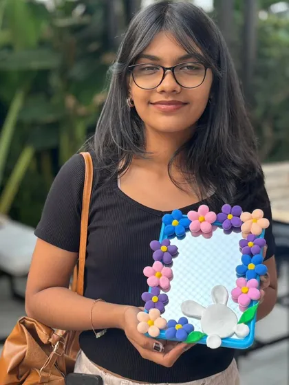 A participant with her finished clay mirror, decorated with pastel flowers and a bunny. A sweet and personal piece of home decor.
