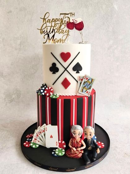 A fun and stylish cake for a 75th birthday. This two-tiered, casino-themed cake features playing cards, poker chips, and cute figurines of the couple.