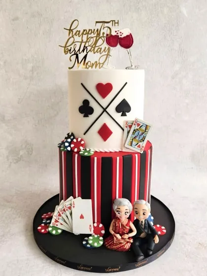 A fun and stylish cake for a 75th birthday. This two-tiered, casino-themed cake features playing cards, poker chips, and cute figurines of the couple.