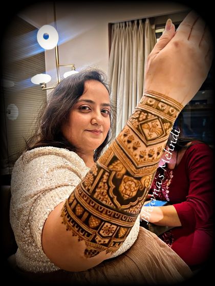 A happy client showing off her detailed arm mehndi. This design is perfect for a bride or a close family member attending a wedding.
