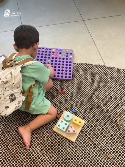A quiet moment of focused play during our summer camp. This child is exploring shapes and patterns, demonstrating how our programs provide a balance of energetic group activities and calm, individual exploration.