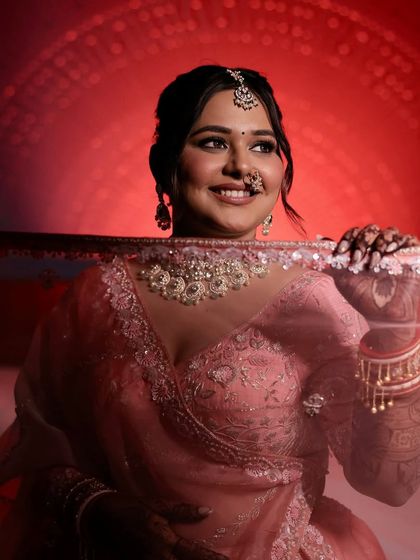 A playful and artistic shot with the veil. The red-toned lighting highlights the soft glam makeup and the bride's happy smile.