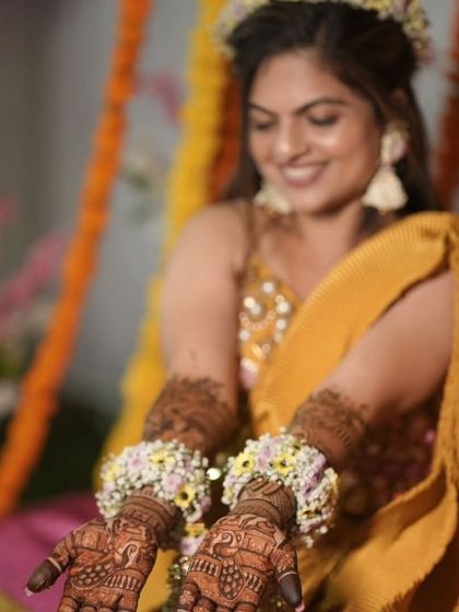 A close-up of the bride's hands, showing the detailed patterns and the beautiful floral jewelry she's wearing.