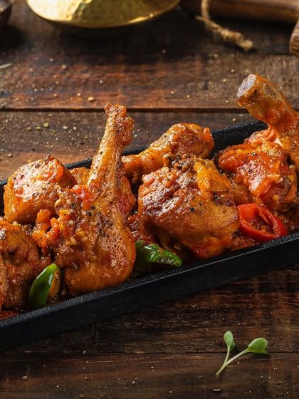 A platter of chicken pieces in a thick, savory sauce, photographed for Punjab Grill's menu.