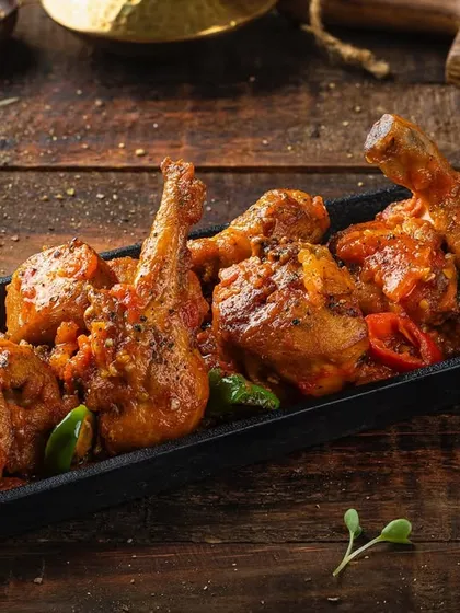 A platter of chicken pieces in a thick, savory sauce, photographed for Punjab Grill's menu.
