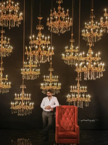 A formal and dramatic series of a model in a black sherwani. The shots are taken in unique studio settings, one with dramatic blue spotlights and another with a wall of chandeliers, creating a high-end, luxurious feel.
