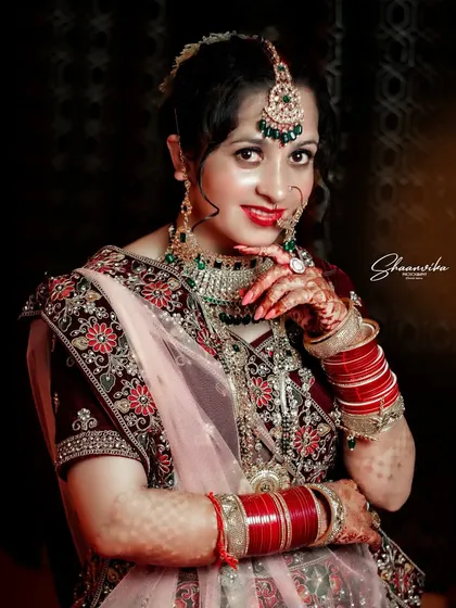 A beautiful three-quarter portrait of the bride, showcasing her elegant pose and the rich details of her embroidered lehenga.