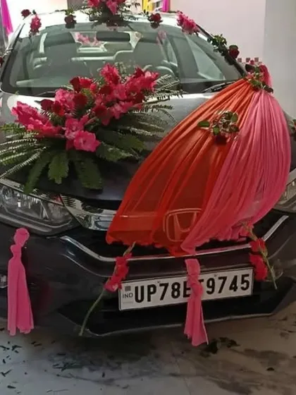 We provide wedding car decoration services for the baraat or vidaai. This Honda City is decorated with large bouquets of fresh red flowers and elegant pink and red fabric draping on the hood.