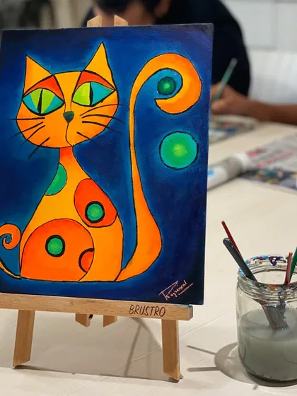 A vibrant, abstract cat painting created on a small canvas. The bold colors and whimsical style perfectly capture the fun spirit of our studio.