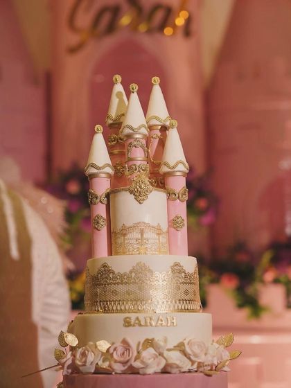 A close-up of the incredibly detailed castle cake from Sarah's party, featuring delicate piping, gold accents, and sugar roses.