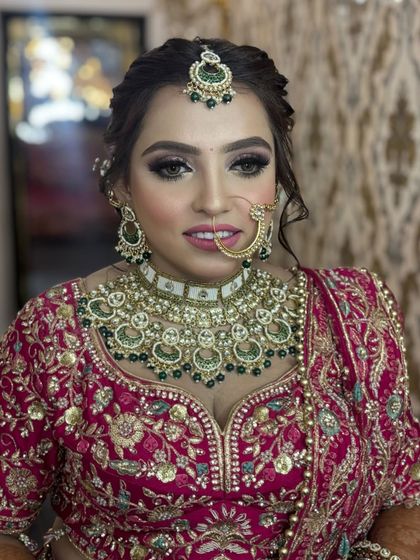 A close-up of a beautiful bride in a deep pink lehenga. Her makeup is classic glam, with defined smokey eyes, a neutral pink lip, and a flawless complexion.