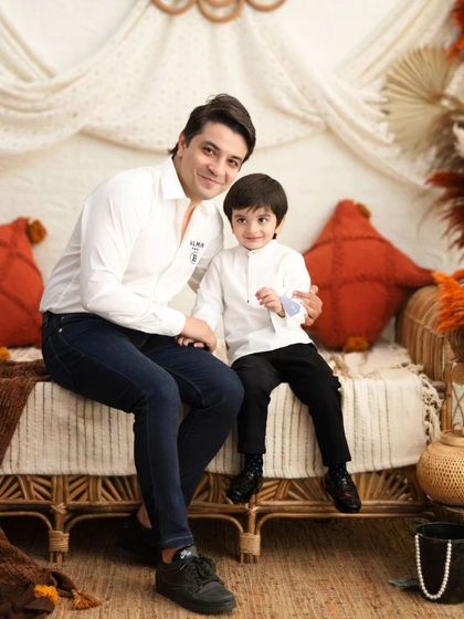 A father and son portrait in a warm, rustic setting. The matching white shirts create a clean and classic look.
