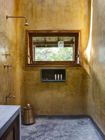 The bathroom of the Garden Suite's blue room, featuring warm, yellow-toned plaster walls and a skylight that fills the space with natural light.