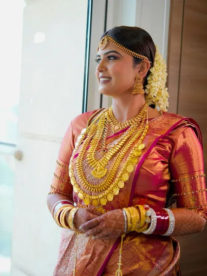 Looking out the window, the bride looks serene and beautiful. Her makeup is designed to look stunning in natural light, highlighting her glowing skin.