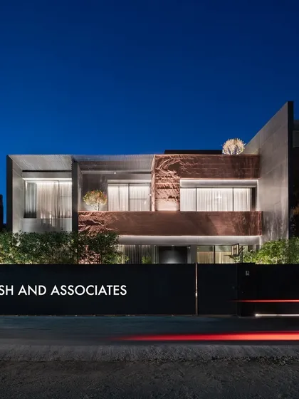 This residence facade showcases a stunning blend of naturally textured red stone and sleek grey tile, creating a beautiful contrast of color and texture.