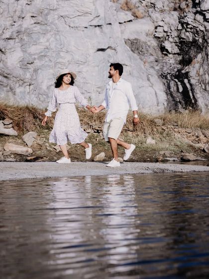 A playful shot of a couple running along the water's edge at a quarry, with their reflection visible in the water.