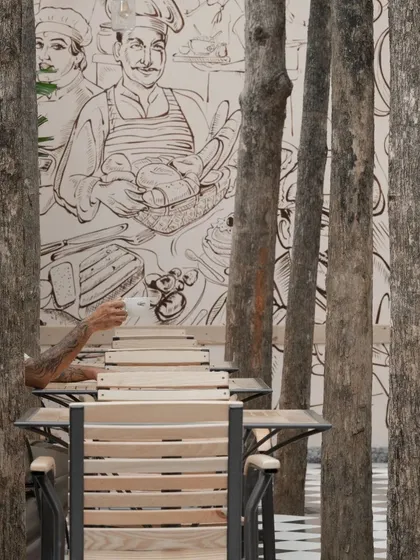 A close-up of the outdoor seating, where a custom mural provides a whimsical backdrop. The existing tree trunks become an integral part of the spatial experience.