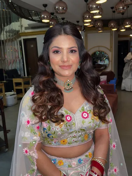 A fresh and vibrant look for a daytime event. The makeup is light and airy, paired with soft curls and a beautiful floral lehenga.