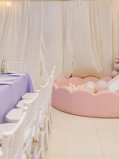 A view of the princess party layout, showing the elegant dining tables alongside the inviting pink ball pit with a slide.