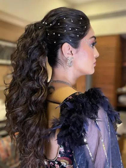 It's all in the details. This chic and playful hairstyle, a voluminous curly ponytail accented with delicate pearls, was designed to complete a glamorous Sangeet look, ensuring she looked stunning from every angle.